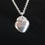 Load image into Gallery viewer, Tiny Sacred Heart pendant in solid sterling silver.

This little silver charm of a flaming heart is 1/2" x 3/8" in size and comes on a silver 18" chain with a lobster clasp.
