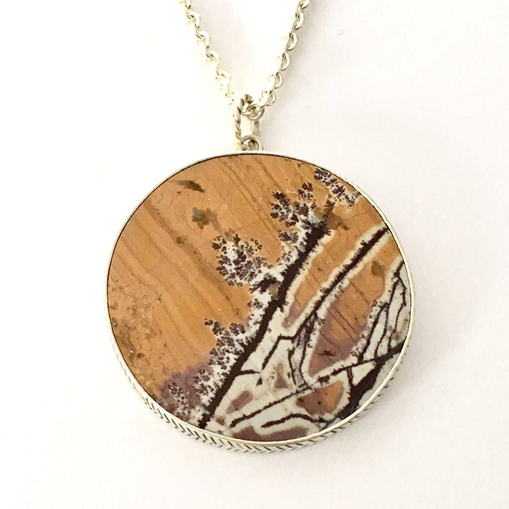 The stone is called Dendrite Rhyolite from the Sonora Desert.  It has the most amazing patterns. The background looks like wood grain and the dendrites are a crackling branch going through out. The colors are tan, burgundy, pinks and whites.