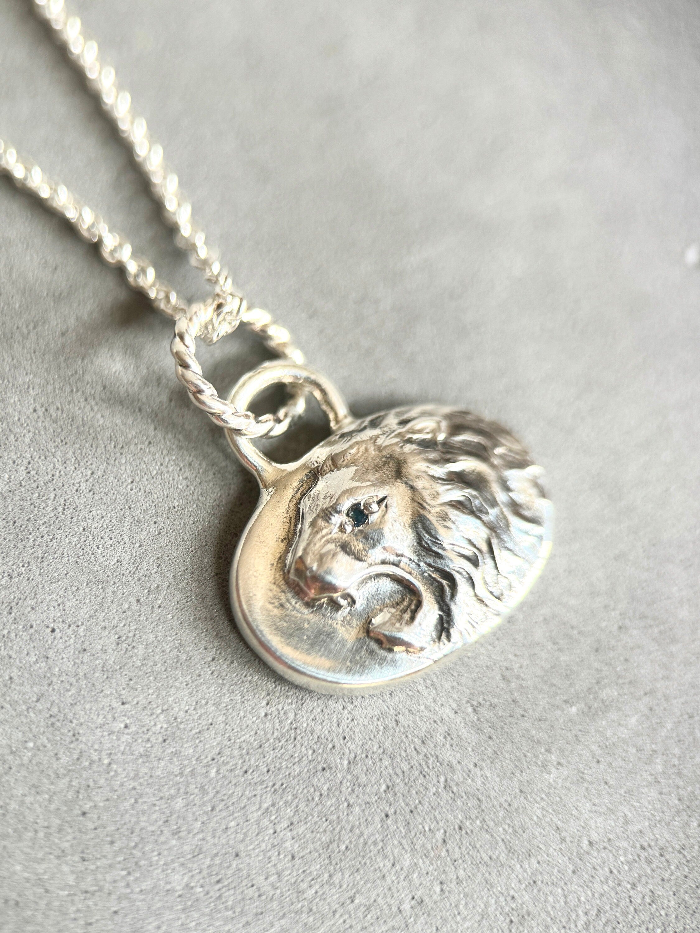 Roaring lion pendant in sterling silver with blue sapphire eye.