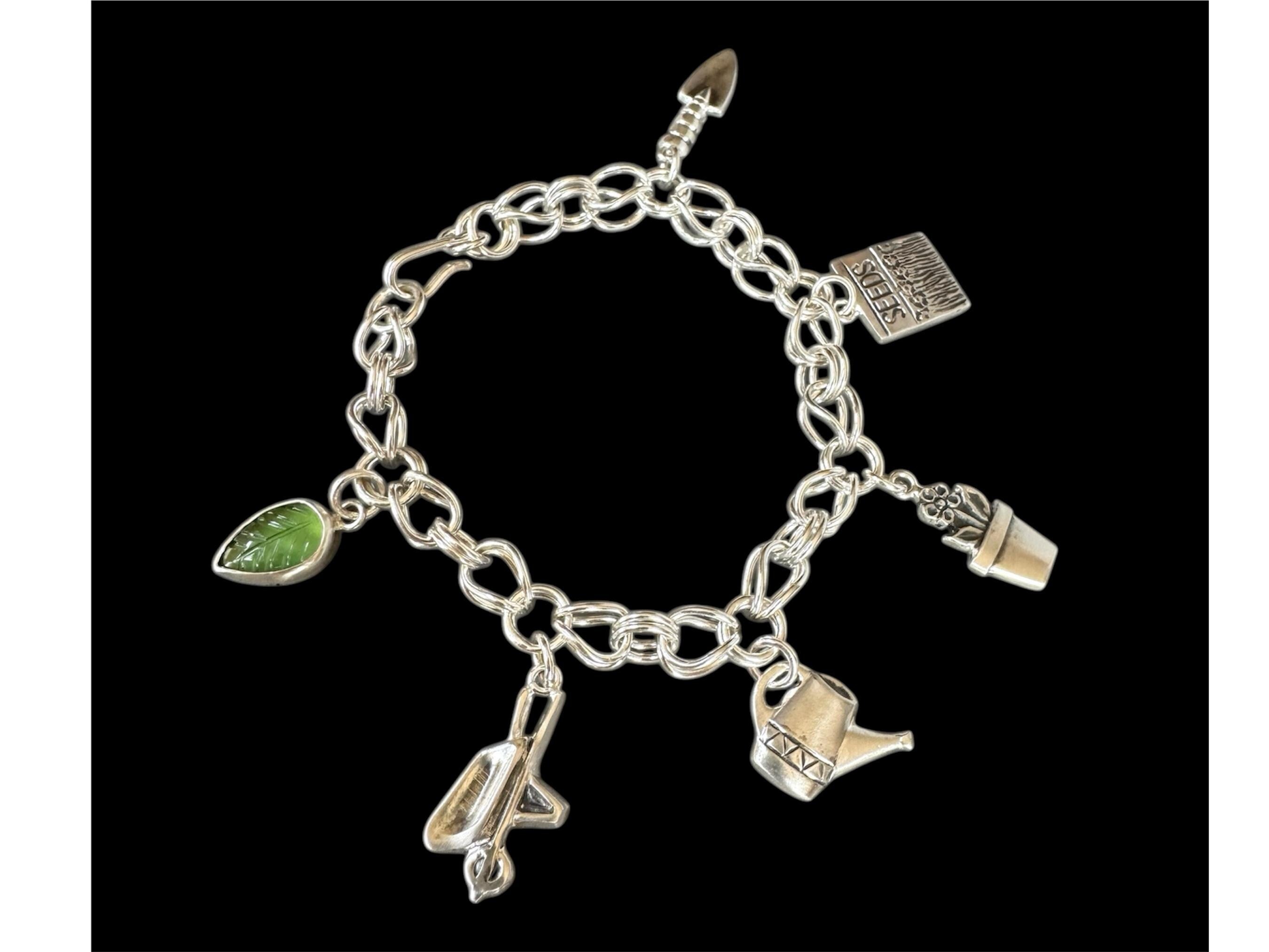 Gardening Charm bracelet. Handmade sterling silver chain with six charms. Trowel, seed packet,flowerpot, wheel barrel , watering can and a gemstone leaf.