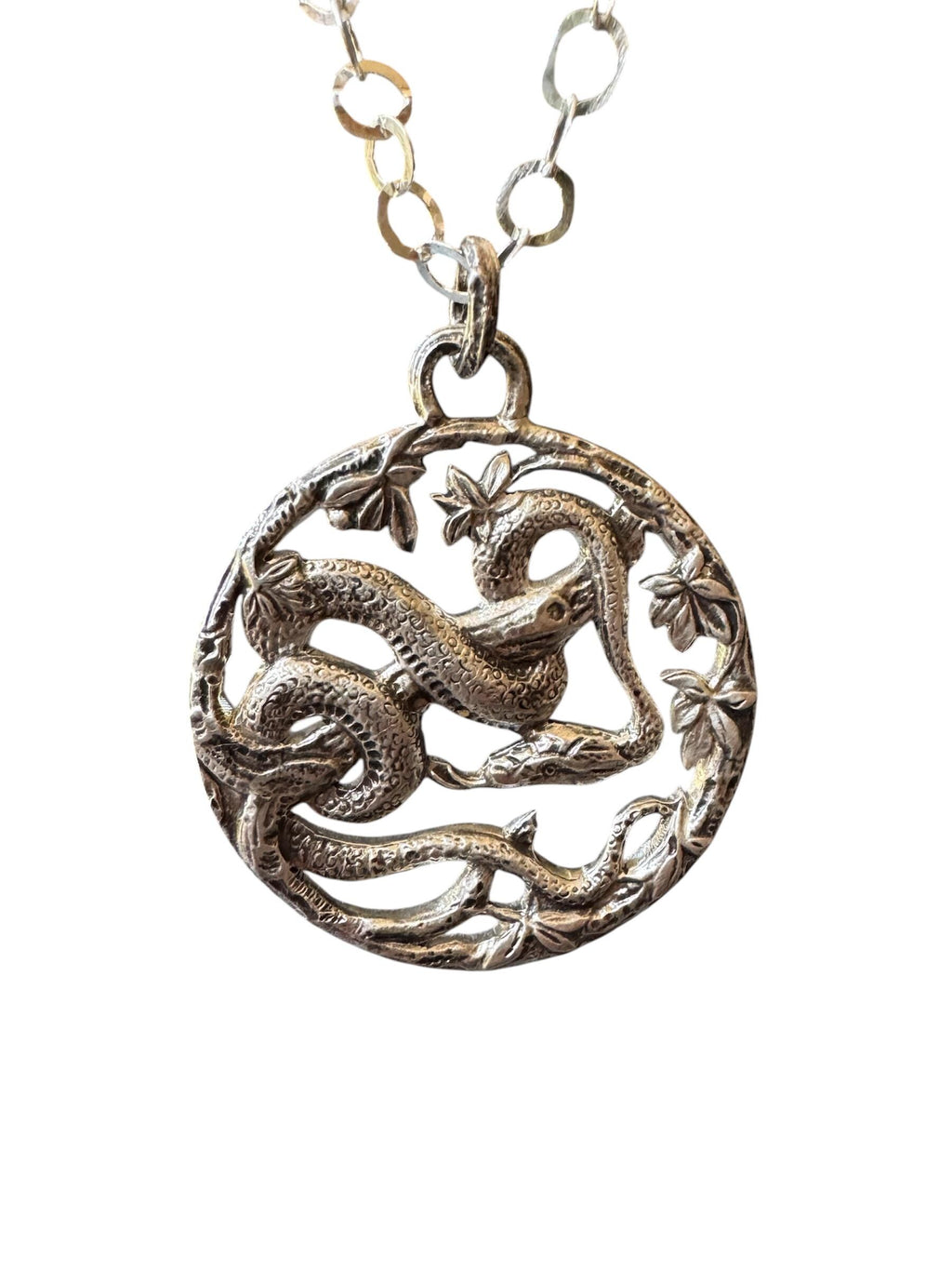 A snake wrapped around a branch and leaves in sterling silver. Pendant made from pressing into a vintage, hand carved die.